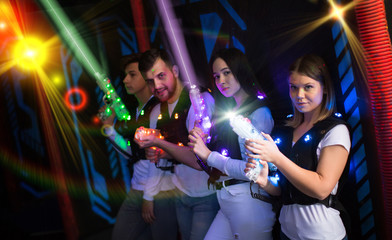 Young people with laser pistols in bright beams