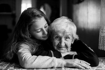 Portrait of an elderly gray-haired woman with her beloved granddaughter. Black and white photo.