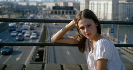 attractive girl in white top holds hand on trestle handrails
