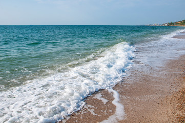 .Sea shore waves sand stones beautiful clouds on blue sky.