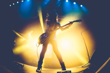 Silhouette of an unrecognizable woman playing the electric guitar