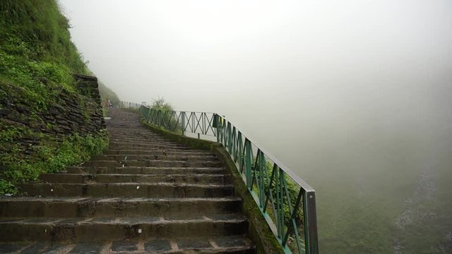 Stairs on plant covered mountains surrounded by fog on the bhagsu trek in Mcleodganj himachal pradesh India