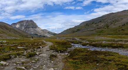 Hiking trail through a panoramic Rocky Mountain landscape with a white clouds, mountains and hills.