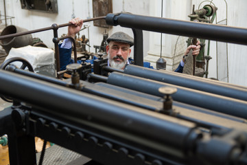 Retro picture of a man working on old printing press