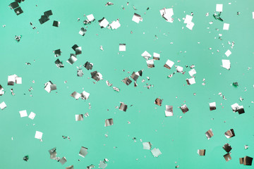 Falling silver confetti on mint backdrop. Holiday concept.
