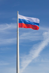 flagpole with waving Russian flag against the blue sky