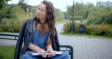 pretty girl in black leather jacket opens modern laptop