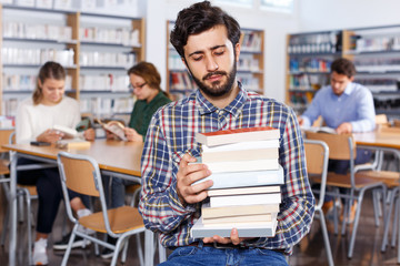 upset man with stack of books in hands