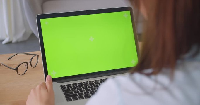 Closeup back view portrait of young caucasian female doctor using laptop with green screen indoors in office