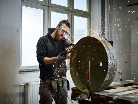 Man working on metal container with grinder