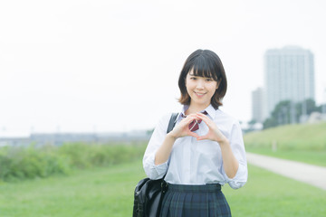 手で「マル」を作る女子高生
