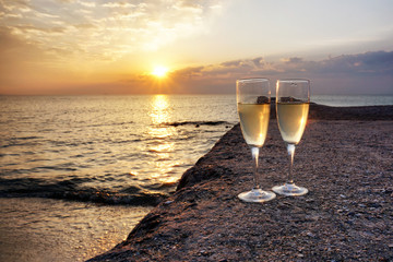 Two glasses of champagne on the beach at sunrise