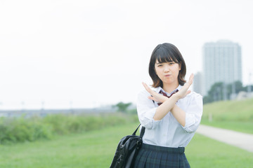 手で「バツ」を作る女子高生