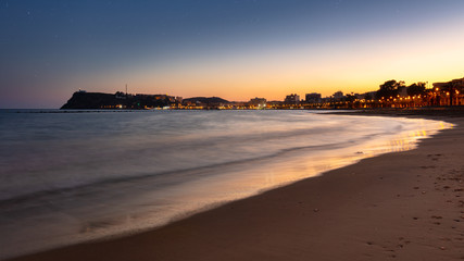 Panoramic view over the bay of the spanish town Mazarron at the mediterranean sea after sunset. Warm orange light and the lighthouse high on the cliffs.
