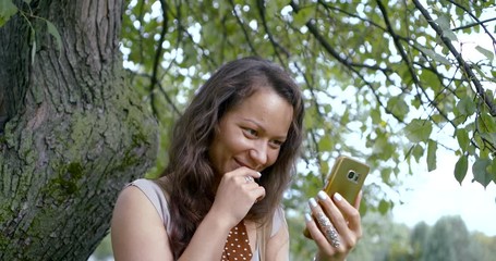 long haired brunette talks on smartphone and types