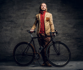 Fototapeta na wymiar Modern bearded hipster in red sweater is holding his bike while posing for photographer.