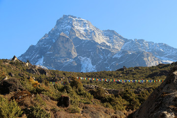 View of Khumbila mountain peak from the plain above the Namche Bazaar town in Himalayas in Nepal. Nature, mountains, rural landscape, outdoors, travel and tourism concept.