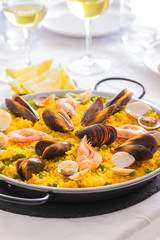 Seafood Paella, famous Spanish  rice dish in traditional frying pan. Paella valenciana with pink prawns, clams and mussels on saffron rice with vegetables.