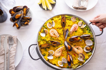 Top view of Seafood Paella with  prawns, clams, mussels on saffron rice and vegetables served in  traditional frying pan on the table.