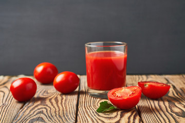 One full glass of fresh tomato juice lies on old rustic wooden table