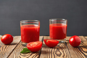 Two full glasses of fresh tomato juice lies on old rustic wooden table