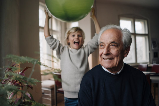Portrait of smiling senior man with grandson holding balloon in background