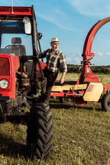 self-employed senior farmer near modern red tractor