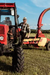 Photo sur Plexiglas Tracteur self-employed senior farmer near modern red tractor