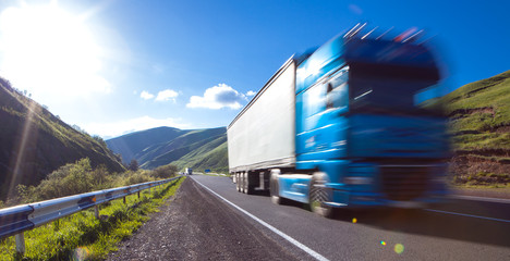 White truck arriving on asphalt road in rural landscape