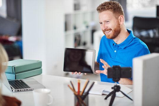 Handsome Caucasian focused employee holding tablet and trying to convince female client to buy stocks.