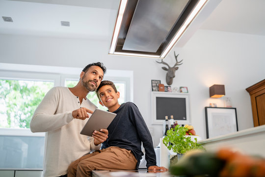 Father and son using tablet in kitchen