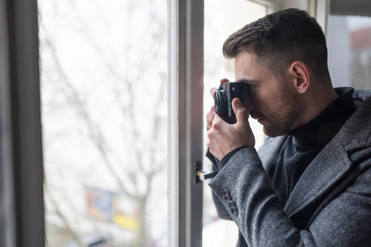 Young man taking pictures at the window