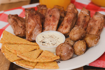 Baked ribs with nachos and sauce.