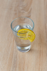 Glass with water and lemon on wooden table