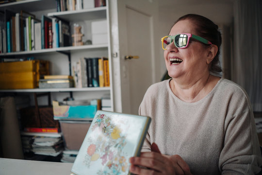 Happy senior woman wearing broken sunglasses at home