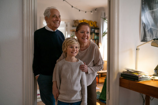 Portrait of happy grandparents with grandson at home
