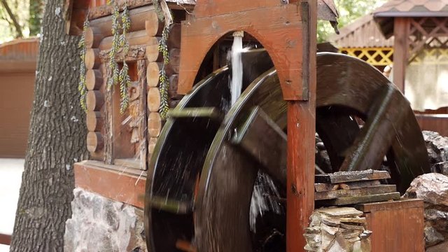 A wooden wheel produces energy using the power of water an old traditional mechanism. Wooden ring rotates with the power of water