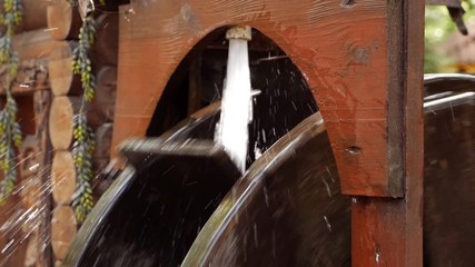 A wooden wheel produces energy using the power of water an old traditional mechanism. Wooden ring rotates with the power of water