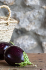 Top view of organic eggplants with basket on wooden table with copy space