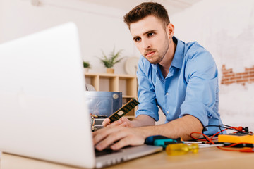 Technician repairing a desktop computer, using laptop