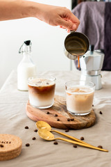 Cappuccino in a tall glass on a table with coffee poured over