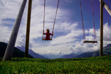 Kind auf einer Schaukel in den Alpen
