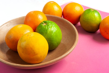 Fruit in clay bowl, rustic, handcrafted.Fruit orange, lemon.Cassis color background.View from the top. From above. Text space.