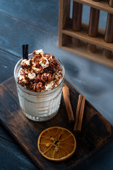 Caramel milkshake with ice cream and popcorn, served in glass with a straw on wooden background