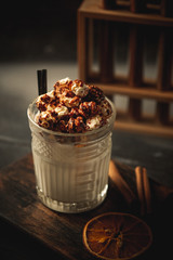 Caramel milkshake with ice cream and popcorn, served in glass with a straw on wooden background
