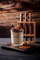 Caramel milkshake with ice cream and popcorn, served in glass with a straw on wooden background