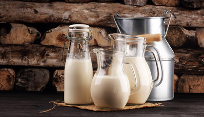 A jug of milk and glass of milk on a wooden black table
