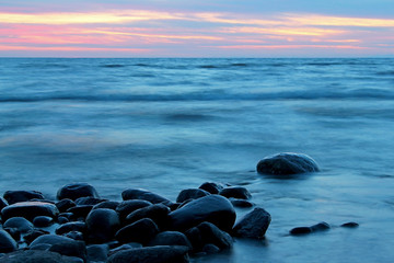 Sunset over the  sea. Coastal landscape of beach with huge boulders in water at sunset, Baltic sea, Latvia.