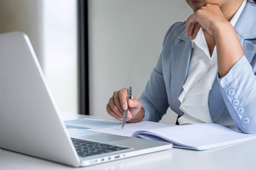 Business woman accountant financier working audit and calculating expense financial annual report balance sheet statement, doing finance checking document and making notes on report paper