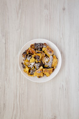 Homemade german Kaiserschmarrn pancake on a white plate on a white wooden background, top view. Flat lay, overhead, from above.